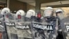 Detalj sa protesta ispred Skupštine Grada Novog Sada, u decembru 2024. Policija, u punoj opremi za razbijanje demonstracija, obezbeđivala je ulaz u zgradu, dok su demonstranti, koji su tražili ostavke gradskih čelnika, njihove štitove izlepili simbolom protesta - crvenim šakama.