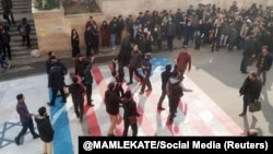 Several people walk on U.S. and Israeli flags while many others avoid stepping on the flags by walking around them, at the Shahid Beheshti University in Tehran, January 12, 2020