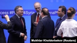 Syrian UN ambassador Bashar al-Jaafari (center) speaks with other participants during a session of the peace talks on Syria in Nur-Sultan in April.