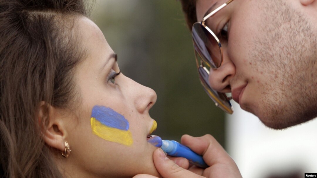 A man paints the colours of the Ukrainian national flag on a woman's face at the Euro 2012 fan zone in Kharkiv.