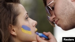 A man paints the colours of the Ukrainian national flag on a woman's face at the Euro 2012 fan zone in Kharkiv.