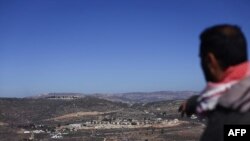 Un palestinian arată reporterului AFP o așezare evreiească lângă satul arab As-Sawiyah, la sud de Nablus, în Cisiordania, la 29 noiembrie 2023. (Foto: Kenzo TRIBOUILLARD / AFP)