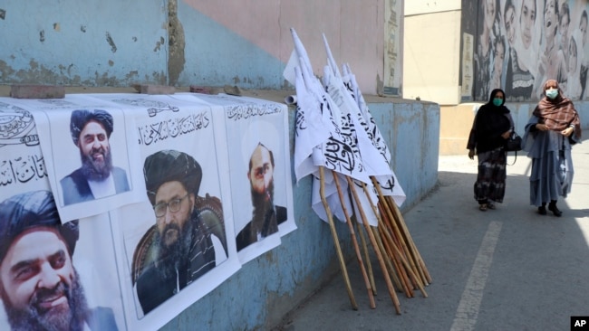 Əfqan qadınlar Kabildə Taliban liderlərinin posterlərinin və bayraqlarının yanından keçirlər.