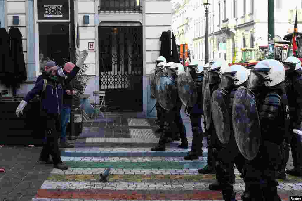 Un protestatar face un gest în fața ofițerilor de poliție.
