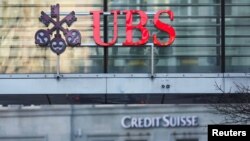 Швейцариянын Цюрих шаарынын көчөлөрүндөгү UBS жана Credit Suisse банктарынын эн белгилери. 20-март, 2023-жыл. REUTERS/ Денис Балибоус.
