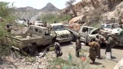 Fighters gather near damaged military vehicles in the aftermath of what a Houthi-owned TV network said were strikes on pro-government forces  in Yemen.