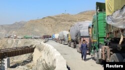 A man walks past trucks loaded with supplies to leave for Afghanistan after Taliban authorities closed the main border crossing in Torkham on February 21.