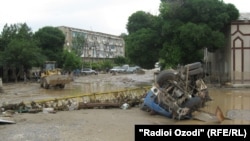 Workers clear debris after flooding in Panjakent.