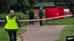 Polițiștii la locul crimei, acoperit cu un cort (în fundal) la Biala Podlaska, în estul Poloniei, pe 16 iunie 2026.