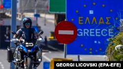 Një burrë nget motoçikletën e tij përpara një tabele të BE-së në hyrje të Greqisë në pikën kufitare 'Evzoni' midis Maqedonisë së Veriut dhe Greqisë.