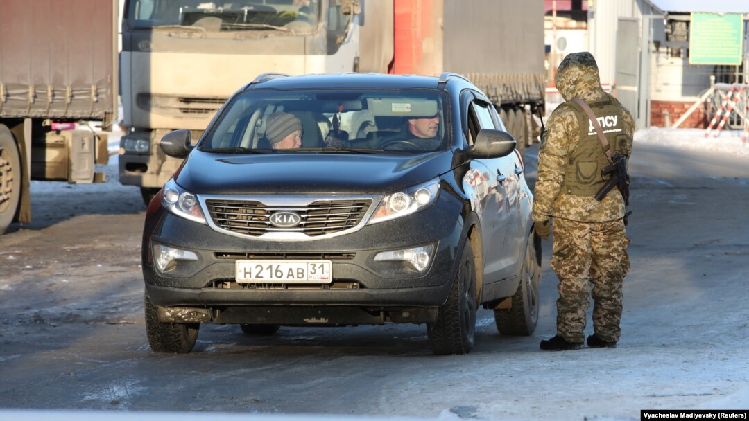 A Ukrainian border guard checks a car with a Russian number plate at a crossing point on the border between Russia and Ukraine in Kharkiv on November 30.