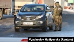 A Ukrainian border guard checks a car with a Russian license plate at the Goptovka crossing point on the border between Russia and Ukraine in the Kharkiv region on November 30.