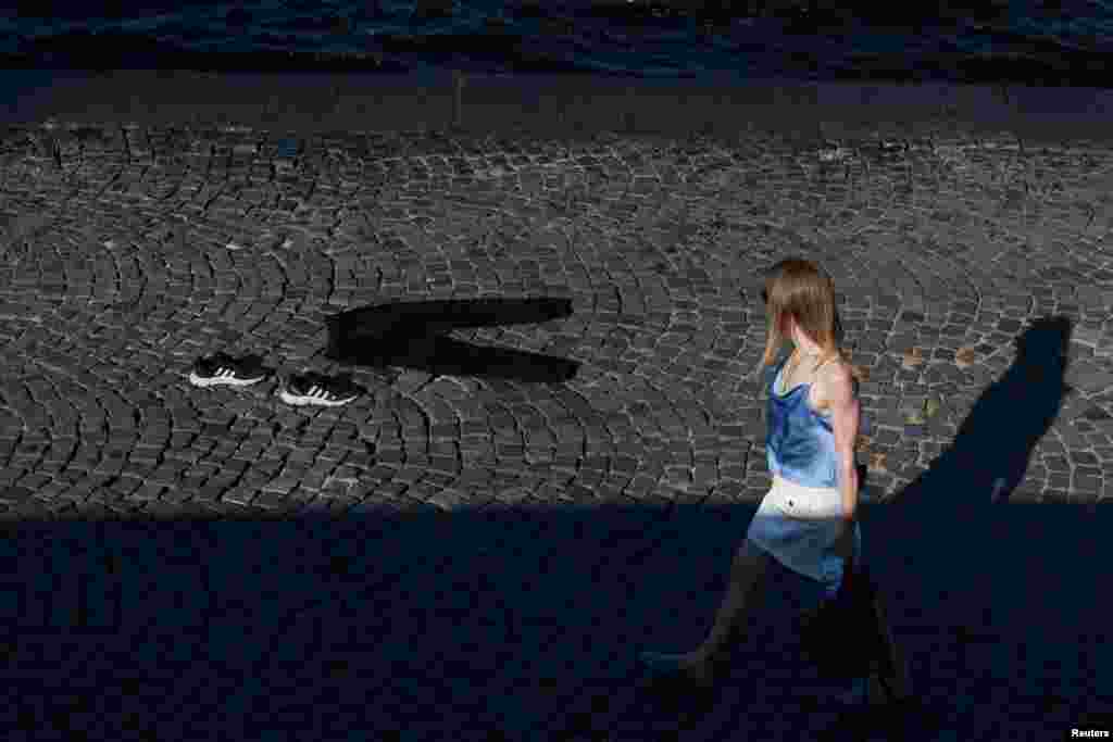 A woman walks past clothes laid out to dry during a hot day in Saint Petersburg, Russia.