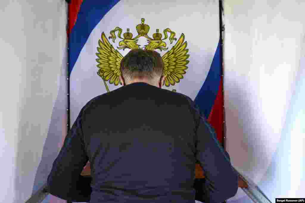 An oil worker reads his ballot in a voting booth during early voting in Russia&#39;s parliamentary elections in the Tyumen region on September 16.