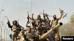 Muammar Kaddafiniň garşysyna söweşen gozgalaňçylar onuň ölümini eşidenden soň, Sirt şäheri. 2011-nji ýylyň 20-nji oktýabry.