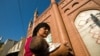 FILE: A young ethnic Uyghur woman carrying a baby walks in front of a mosque in Urumqi.