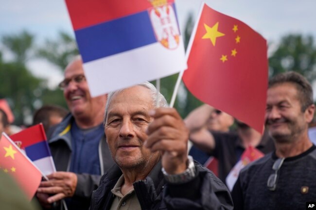 Një burrë valëvit flamujt kinezë dhe serbë gjatë vizitës së presidentit kinez, Xi Jinping, në Serbi, 8 maj 2024.