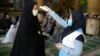 An Iranian woman checks the temperature of a worshipper attending Friday Prayers in a mosque in Qarchak, in Tehran Province, on June 12.