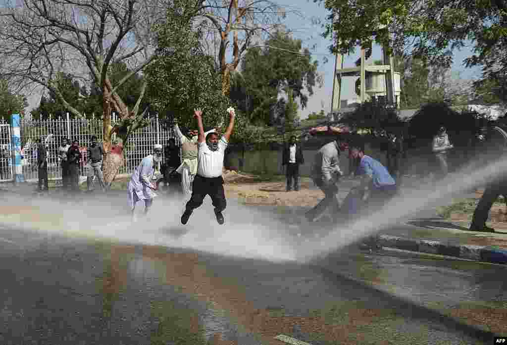 Pakistani employees of Pakistan International Airlines shout slogans as police use a water cannon on them during a protest near Karachi International Airport on February 2. (AFP/Rizwan Tabassum)