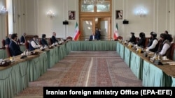 Iranian Foreign Minister Mohammad Javad Zarif (center) addresses delegations of Afghanistan (left) and the Taliban (right) at the Iranian Foreign Ministry in Tehran on July 7.