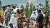 Flood survivors speak with security personnel as they wait for their turn to board army boats while they are evacuated from the flood-hit Chakdarra area of Swat on August 4.