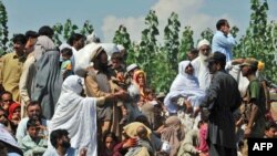 Flood survivors speak with security personnel as they wait for their turn to board army boats while they are evacuated from the flood-hit Chakdarra area of Swat on August 4.