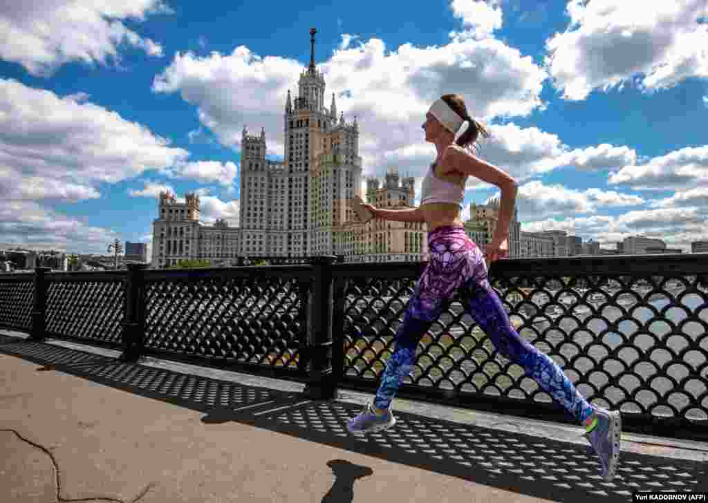 A woman runs along a bridge in front of a Stalin-era skyscraper in central Moscow on June 29. (AFP/Yuri Kadobnov)