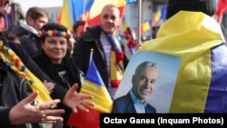 Susținătorii lui Călin Georgescu se îndreaptă spre sediul Guvernului, unde are loc alt protest, al sindicatelor, cu portretul lui Călin Georgescu atașat pe steagul României.