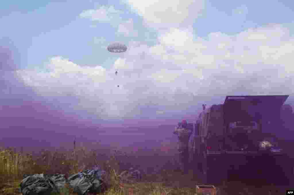 A U.S. Army soldier, part of the NATO-led peacekeeping mission in Kosovo , KFOR, parachutes as others throw smoke grenades during a U.S. military exercise near the town of Gjakova, Kosovo. (AFP/Armend Nimani)