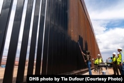 Министр внутренней безопасности США Кристи Ноэм красит пограничную стену в черный цвет. Город Санта-Тереза, штат Нью-Мексико, 19 августа 2025 года