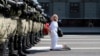 A woman kneels in front of a line of riot police as they blocked tends of thousands of Belarusian opposition supporters rallying in the center of Minsk on August 30.