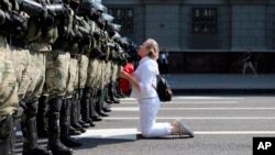 A woman kneels in front of a line of riot police as they blocked tends of thousands of Belarusian opposition supporters rallying in the center of Minsk on August 30.