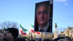 На фотографии, сделанной 4 января 2026 года в центре Парижа, протестующий во время демонстрации против подавления протестов иранским режимом держит плакат с изображением сына последнего шаха Ирана Резы Пехлеви