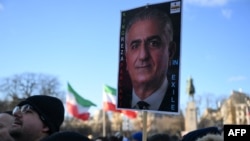 На фотографии, сделанной 4 января 2026 года в центре Парижа, протестующий во время демонстрации против подавления протестов иранским режимом держит плакат с изображением сына последнего шаха Ирана Резы Пехлеви