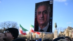 На фотографии, сделанной 4 января 2026 года в центре Парижа, протестующий во время демонстрации против подавления протестов иранским режимом держит плакат с изображением сына последнего шаха Ирана Резы Пехлеви