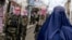 Taliban security officers patrol a street as an Afghan burqa-clad woman walks through a market in the Baharak district of Badakhshan Province. (file photo)