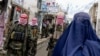 Taliban security personnel stand guard as an Afghan burqa-clad woman walks along a street in northern Afghanistan. (file photo)