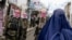 Taliban security personnel stand guard as an Afghan burqa-clad woman walks along a street in northern Afghanistan. (file photo)