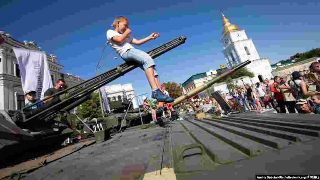 A child plays on a gun at an exhibition of modern weapons and military equipment in Kyiv to coincide with Ukraine&#39;s Independence Day on August 24. (RFE/RL/Andriy Dubchak)