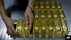 Texniki işçi Dubayda yerləşən "Emirates Gold" şirkətinə çatdırmaq üçün 1 kq qızıl külçəni qablaşdırır.