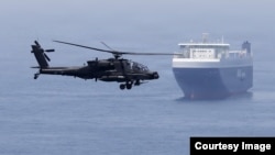 A US Army helicopter escorts a ship through the Strait of Hormuz. (file photo)