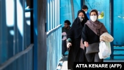 Iranian women wearing protective masks walk in Tehran.