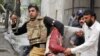 A police officer carries the body of a wounded worshiper at one of two mosques stormed by gunmen in Lahore on May 28.