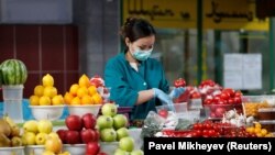 Жеміс-жидек сатып тұрған маска таққан жұмысшы. Алматы, сәуір айы 2020 жыл.