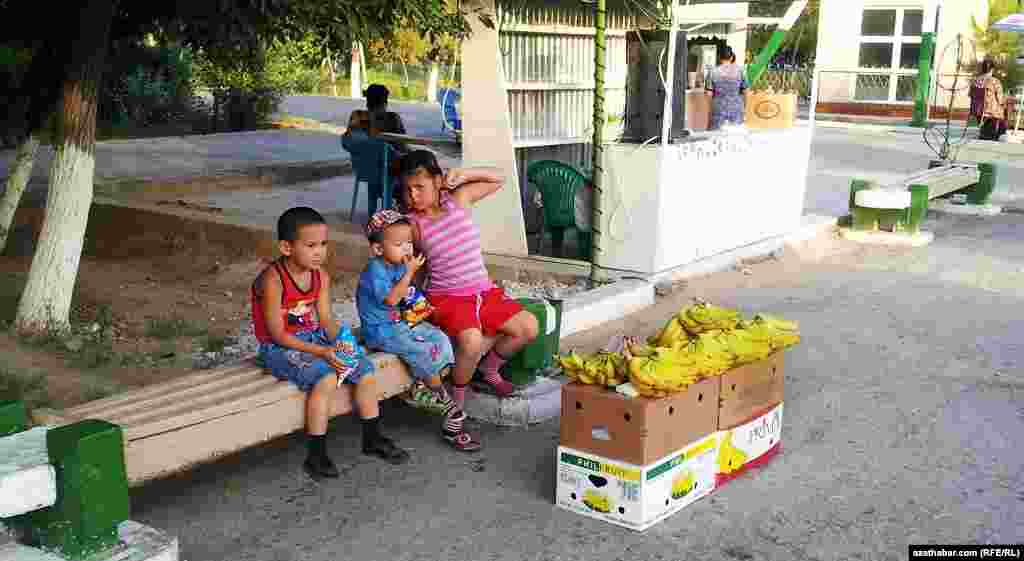 Ýoluň gyrasynda banan satyp oturan çagalar
