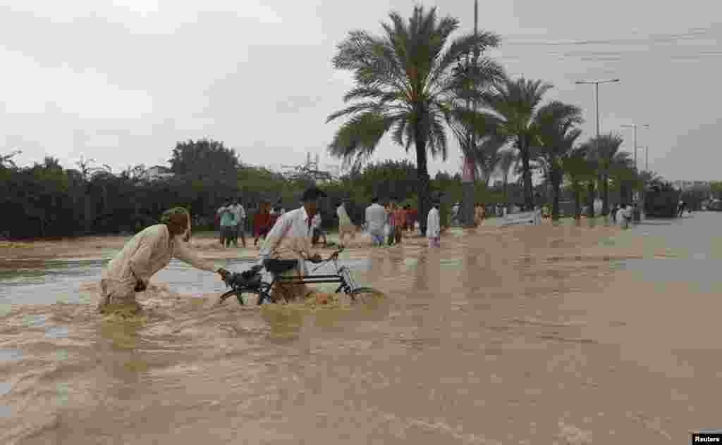 Men push their bicycles through floodwaters on the outskirts of&nbsp;Karachi. 