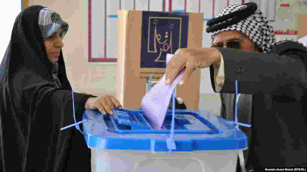 A man casts his ballot in provincial elections under the supervision of a woman election monitor in Karbala.