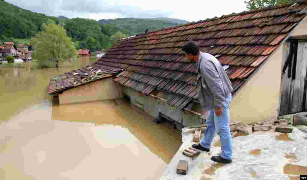 A man stands on a roof in Pozega, Serbia.