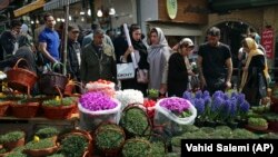 In this March 19, 2018 photo, Iranians shop for hyacinths, garlic, sprouts and other items used to celebrate the Iranian New Year, ahead of the holiday, at the Tajrish traditional bazaar in northern Tehran, Iran