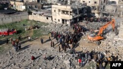 Excavatoarele sapă printre dărâmăturile unei clădiri distruse de bombardamentele israeliene la Rafah. 19 decembrie 2023.